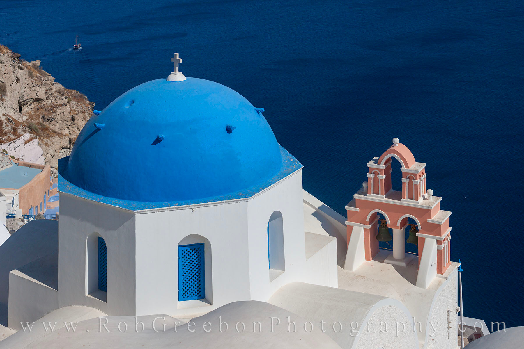 Rooftops of Santorini 1 The blue domes of Oia, Santorin, and the pastel reds of a bell tower make for a nice contrast against the deep blue water of...