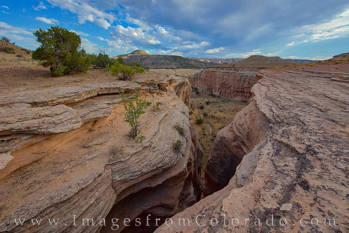 Slot Canyon near Horsethief Canyon 716-1 From the edges of a slot canyon, this photograph looks down into the red standstone walls. In the distance, the valley that holds...